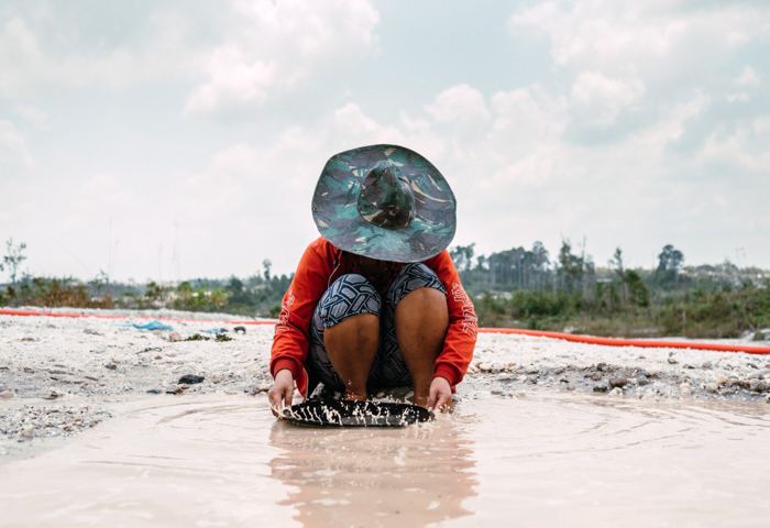 An artisanal miner panning river gravels for alluvial gold