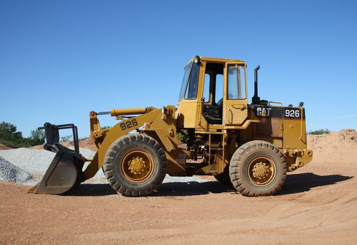 A Caterpillar 926 wheel loader working a red-earth quarry face