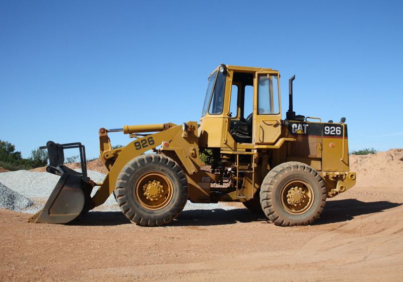 A Caterpillar 926 wheel loader working a red-earth quarry face