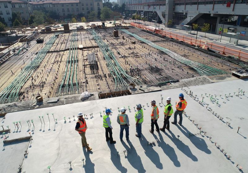 Reinforcement steel laid across a large commercial slab with site crew in high-visibility vests